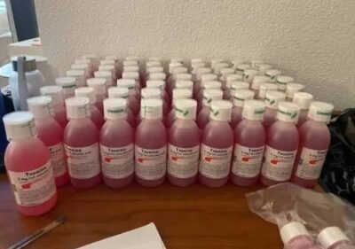 Toseina codeine hoestsiroop fles met maatbeker op een witte achtergrond
